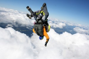 Two skydivers in free fall on a sunny day in cloudy sky head down